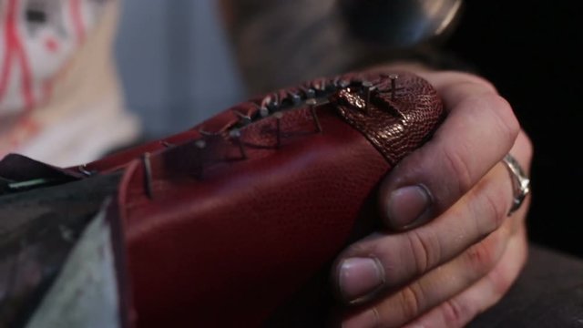 Shoemaker sews shoes. Hammering shoe leather