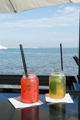 two cocktails in front of water