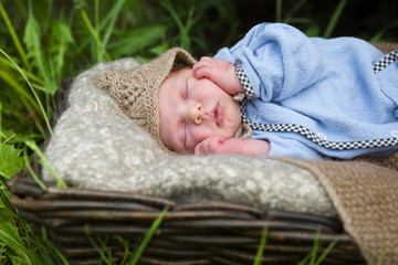 newborn baby in blue suit sleeping in the garden