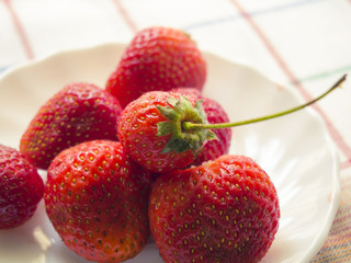 few berries of a fresh strawberry on a white plate