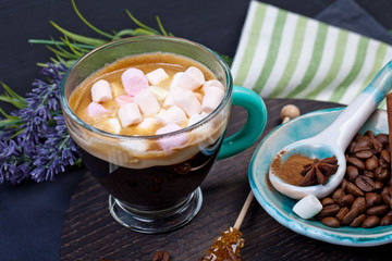 Coffee cup with sugar and spices on a wooden board.