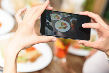 Woman photographing food by smartphone