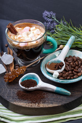 Coffee cup with sugar and spices on a wooden board.