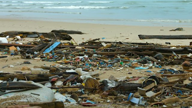 Physical polution in the form of garbage and assorted debris, washed up on the white sand of a tropical beach. UltraHD video