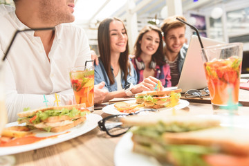 Four friends in coffee shop using laptop