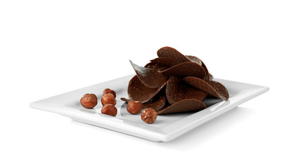 Chocolate chips and hazelnuts in plate on white background