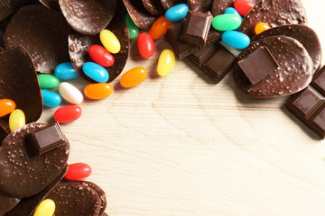 Chocolate chips and colorful candies on wooden background