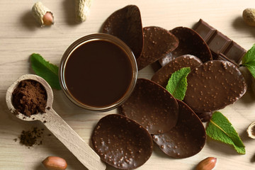 Composition of chocolate chips and spoon with cocoa powder on wooden background