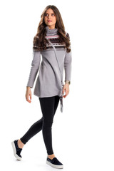 Woman in pullover is walking. Gray sweater and slip ons. New skinny fit pants. Stylish apparel for cool weather.