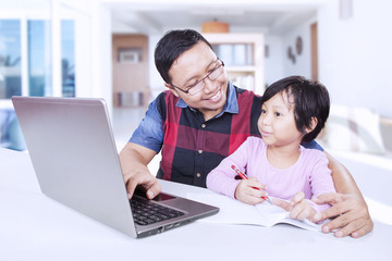 Child studying with her dad at home