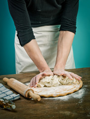 Making dough by mens hands on wooden table background