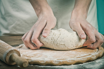 Making dough by mens hands on wooden table background