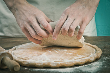 Making dough by mens hands on wooden table background