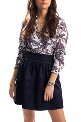 Girl in printed shirt. Skirt of navy color. Gold bracelets and small pendant. Pretty model of fashion magazine.