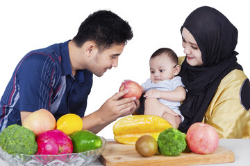 Fototapeta premium Father giving an apple to baby