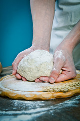 Obraz premium Making dough by mens hands on wooden table background
