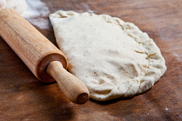 Pizza dough, spices and vegetables on wooden table.