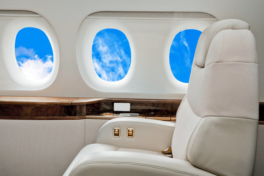 Aircraft business class interior with blue sky outside the portholes