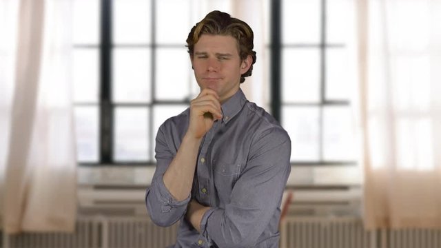 Man looks at camera quizzically near windows