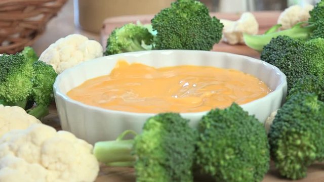 Dipping cauliflower into a cheese sauce, slow motion
