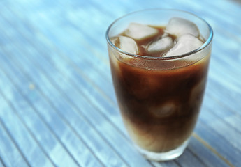 Glass of iced coffee on wooden background