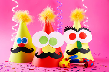 Funny party hats with blowers on pink background