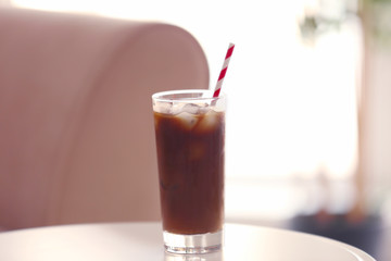 Iced coffee with straw on white table