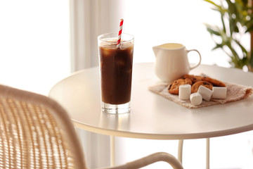 Iced coffee with straw on white table in cafe