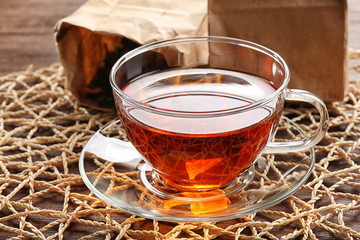 Glass cup of tea with decorative napkin on wooden background