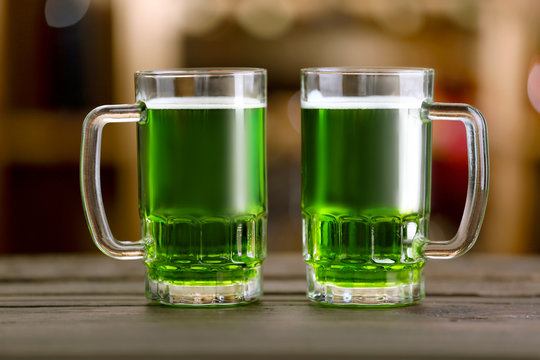 Glasses of green beer on wooden table