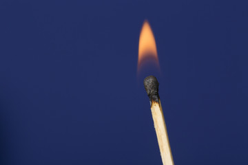 Burning match stick against blue background