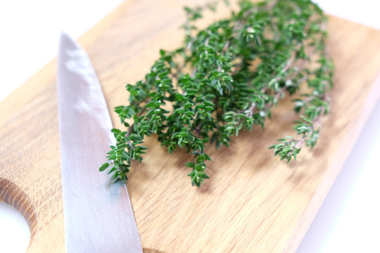 High key image of organic thyme fresh herb on a wooden chopping board with a knife blade. Very shallow depth of field.