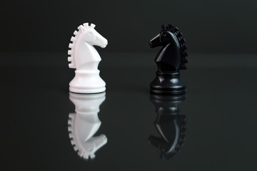 Chess knights facing each other, black background