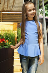 beautiful little girl in blue shirt and jeans with long hair in the sunny interior