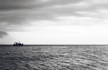 Wooden boat with people in the ocean at sunset