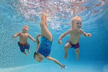 Funny photo of active babies swim and dive with fun - jump deep down underwater with splashes in...