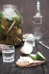 Homemade pickles, bottle of vodka, two glasses and a snack