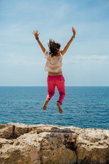 Obraz premium Happy woman jumping against sea