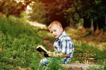 Little boy reading a book in the Park