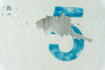 crackled number 5 on the dirty white wall