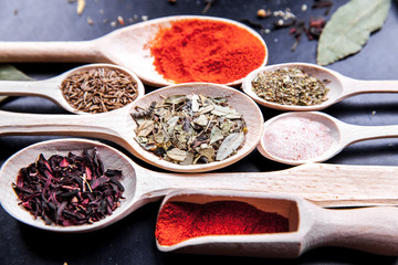 spice in wood spoon on a black background. food