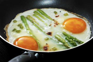 scrambled eggs in a frying pan with asparagus