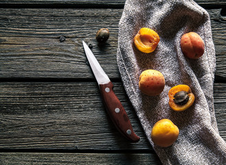 Fresh apricots with a knife on a kitchen towel. Wooden background. Fruit, food