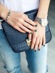 Modern girl with green nail Polish and a trendy bag in stylish j