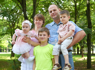 happy family portrait on outdoor, group of five people posing in city park, summer season, child and parent