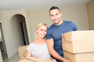 happy young couple carrying cardboard boxes moving into their new house