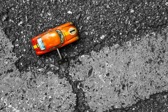 Orange clockwork toy car on asphalt background