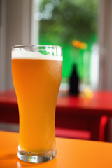 Pint of golden craft beer ale in colorful bar