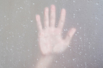 Palm hand behind frosted glass with droplets