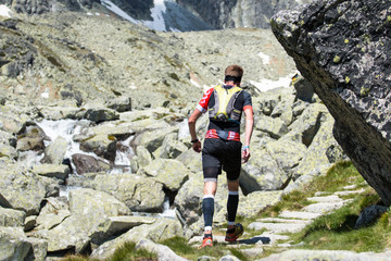 young man in compress socks running near the waterfall in high mountains